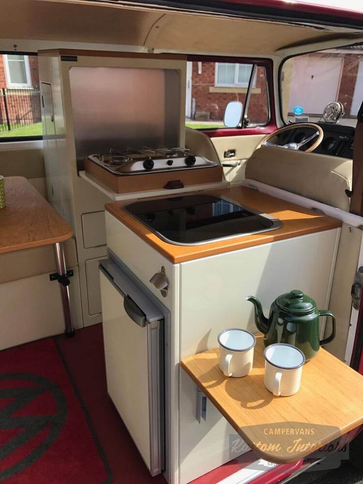 a camper with a stove and two cups on the counter