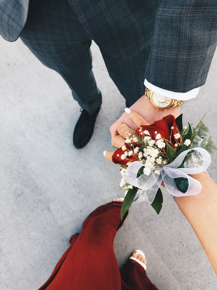 two people holding hands with flowers in their hand and one person wearing a suit standing next to them