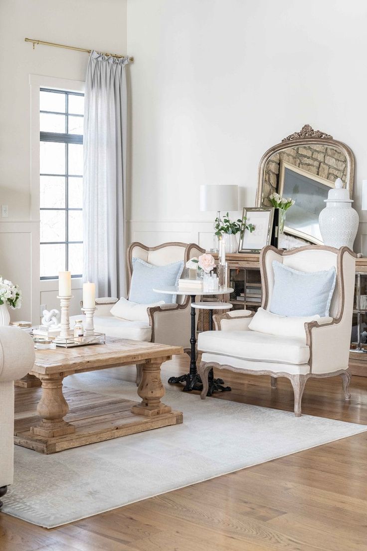 a living room with two chairs and a coffee table in front of a mirror on the wall