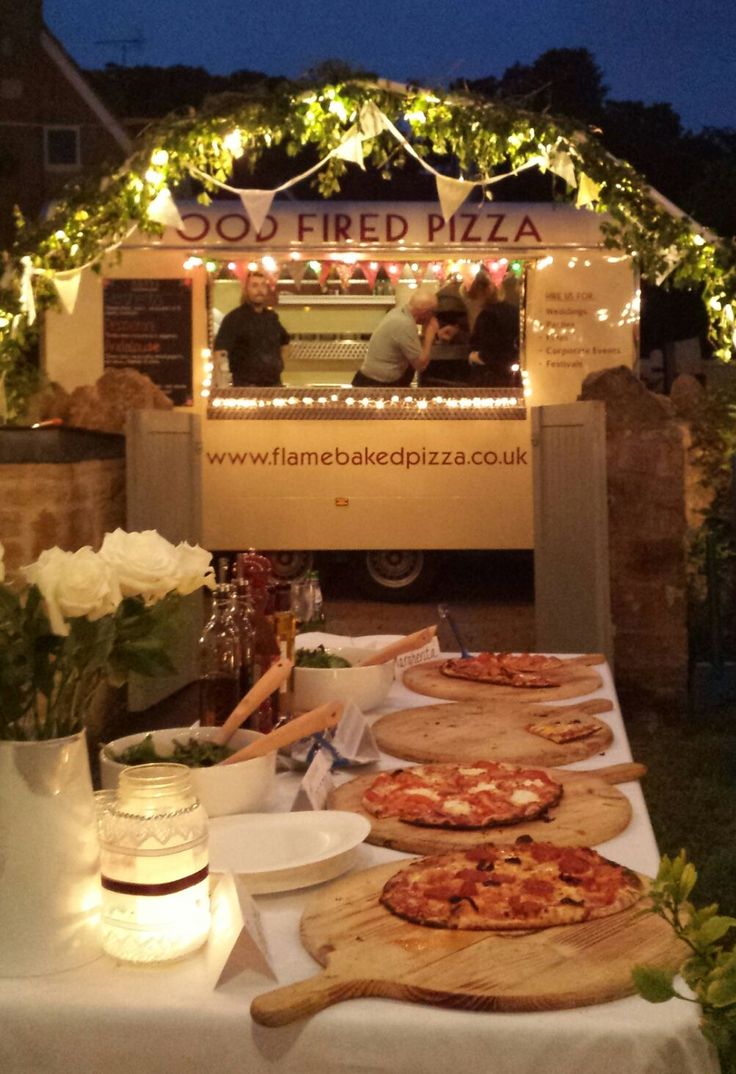 several pizzas sitting on top of a table under a tent with lights around them