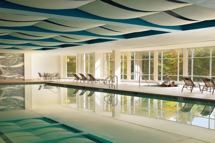 an indoor swimming pool with chairs around it