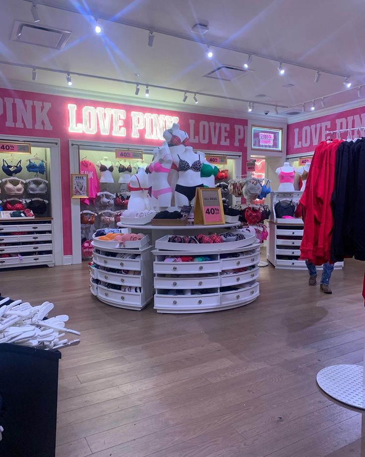 the inside of a clothing store with pink and white items on display in front of them