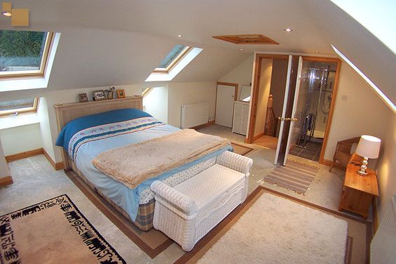 an attic bedroom with skylights and a bed in the corner, rugs on the floor