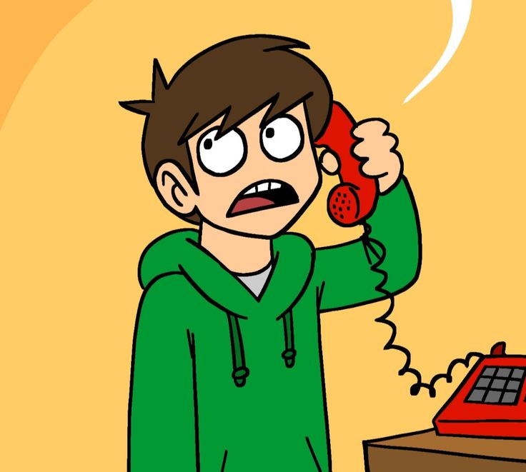 a man holding a red phone up to his ear while standing in front of a desk