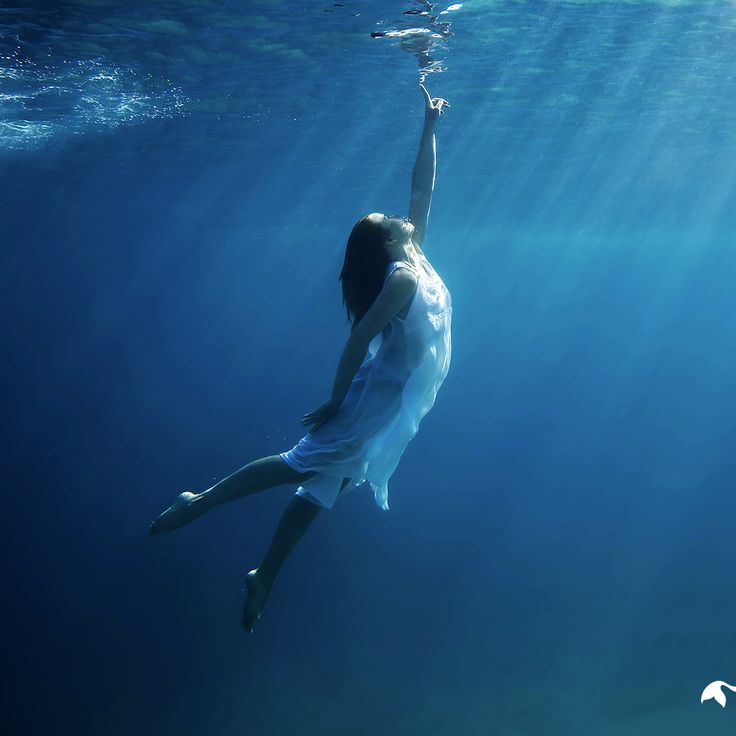 a woman is floating in the water with her arms up