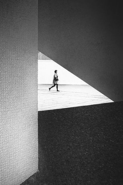 black and white photograph of a person walking in an open space with the door ajar