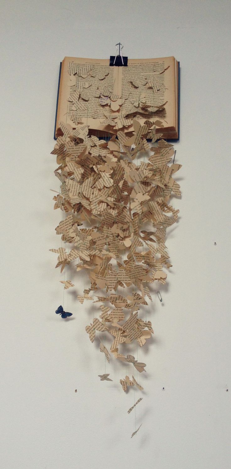 an open book with many pieces of paper cut into the shape of butterflies hanging from it