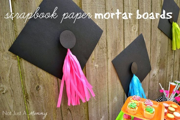 two black graduation caps with tassels hanging on the side of a fence that says scrapbook paper mortar boards