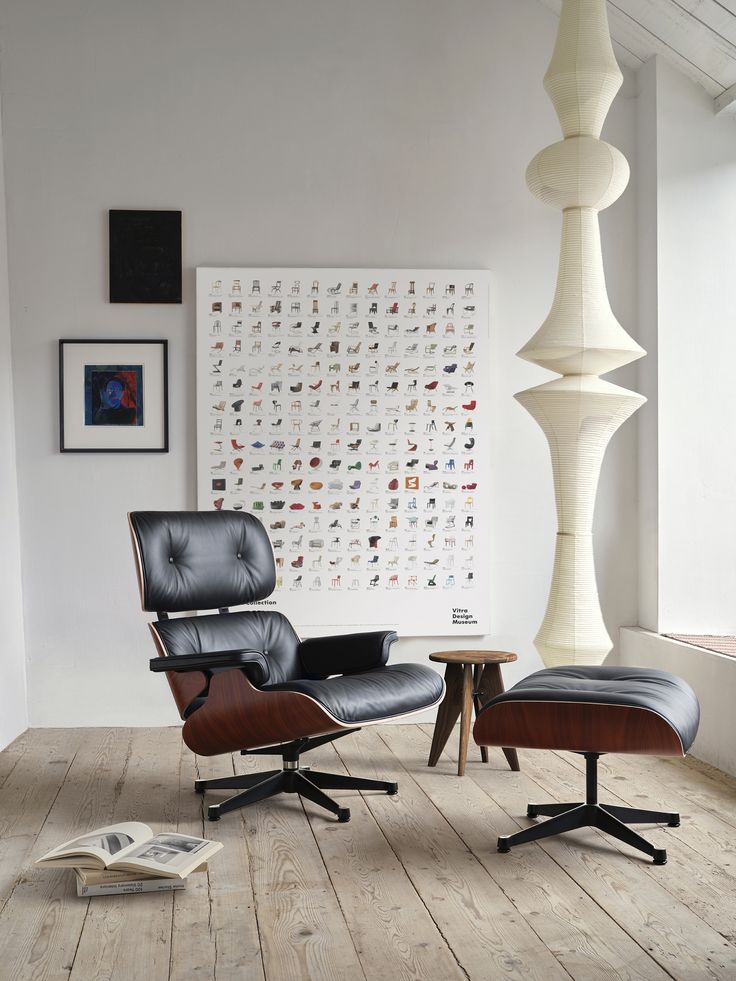 an eames chair and ottoman in front of a large poster