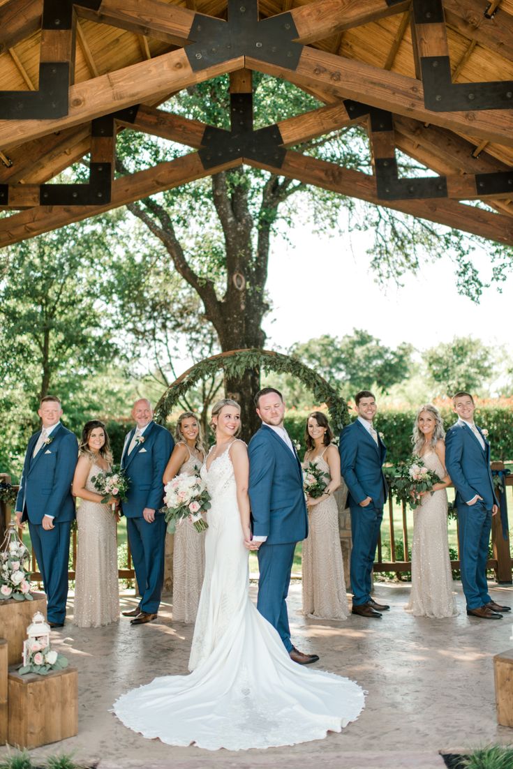 a bride and groom with their bridal party in front of a wooden gazebo