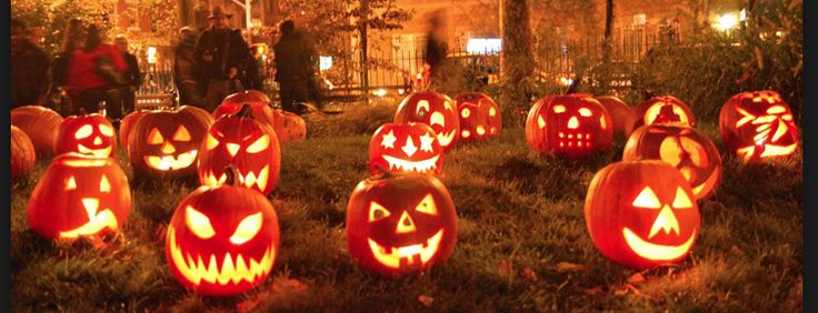 many carved pumpkins are sitting in the grass with their faces lit up at night