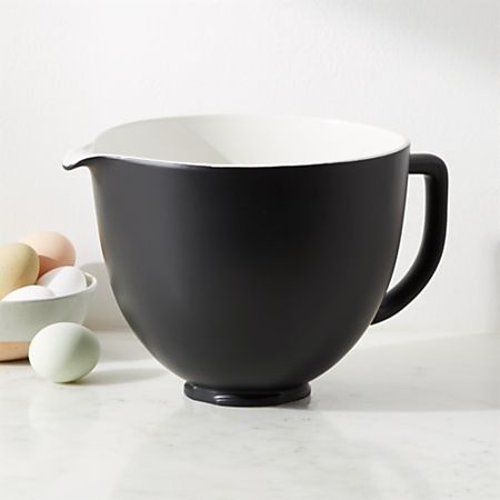 a black and white bowl sitting on top of a counter next to an assortment of eggs