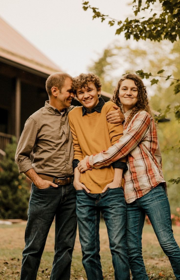 a group of people standing next to each other in front of a tree and building