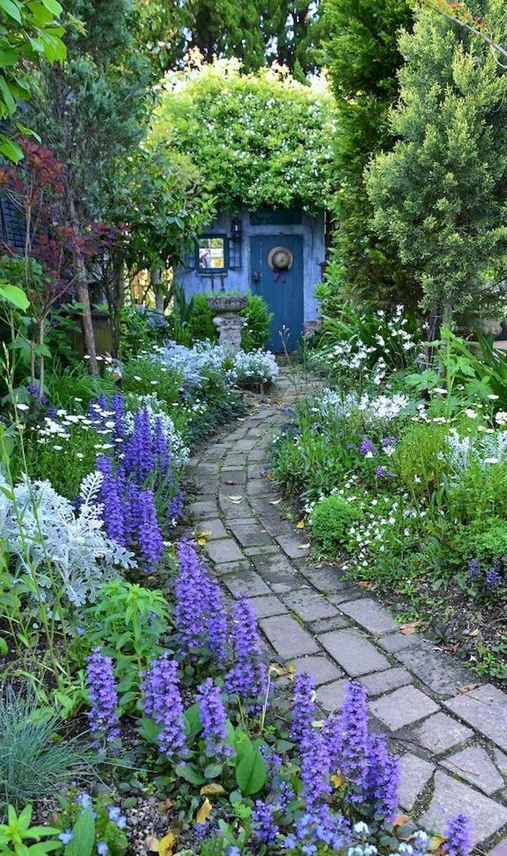 a garden with blue doors and purple flowers in the foreground, surrounded by greenery