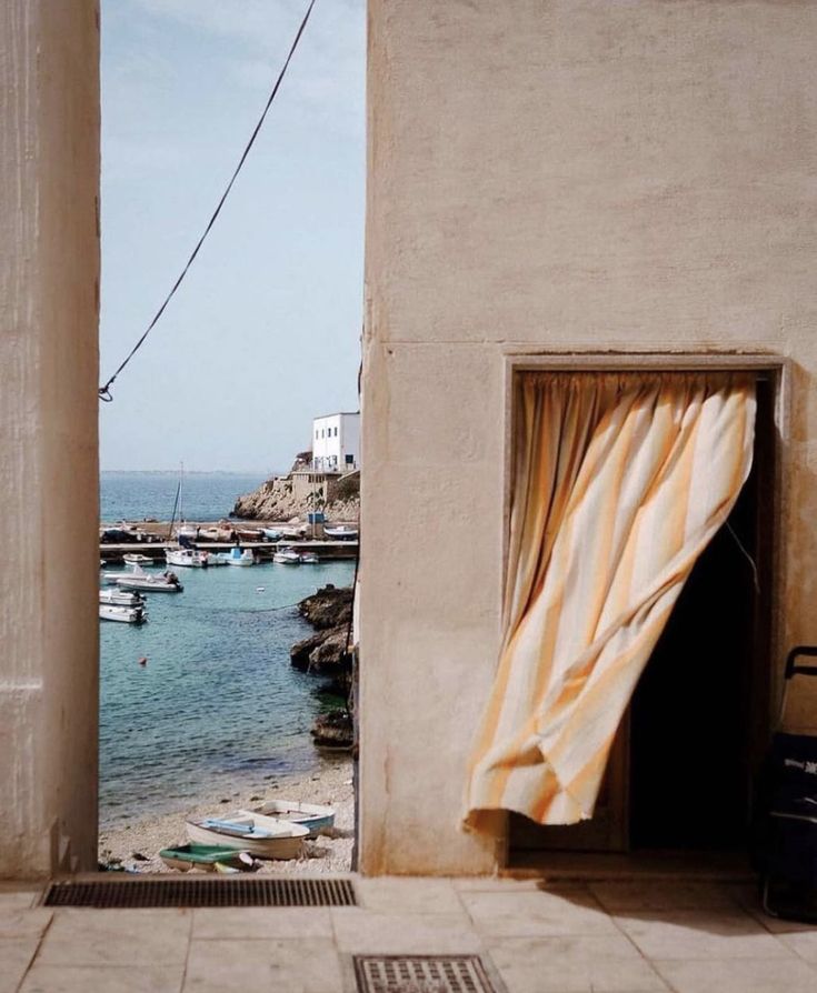 an open door leading to a beach with boats in the water