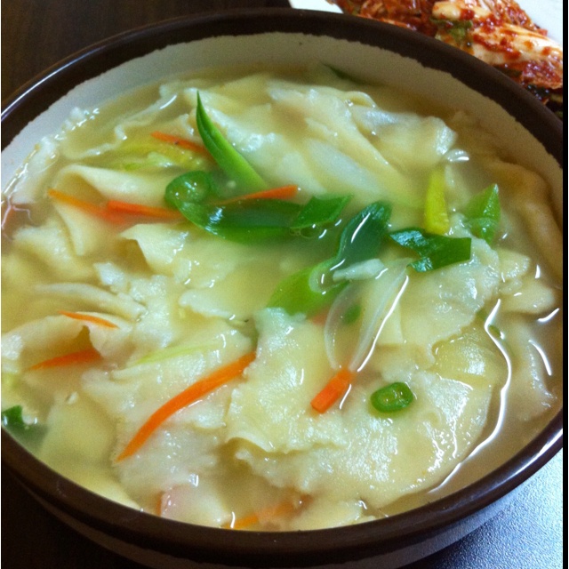 a bowl filled with noodles and vegetables on top of a table next to some bread