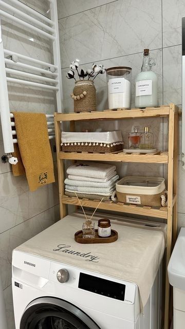 a washer sitting next to a dryer in a bathroom under a towel rack