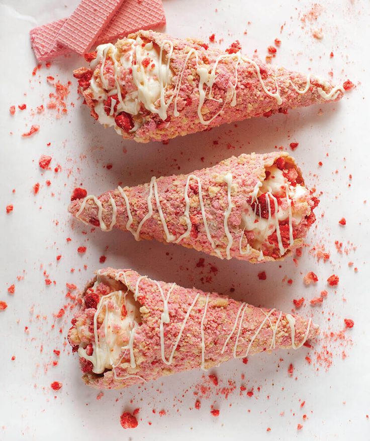 three pieces of food that are on top of a white surface with red sprinkles