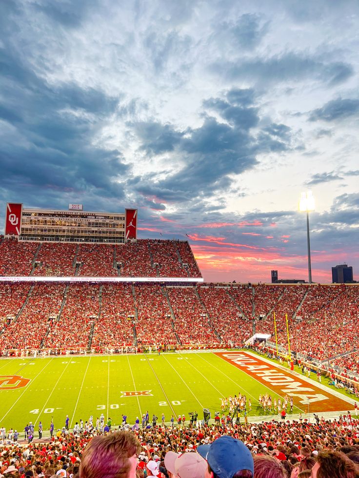 a football stadium filled with lots of people watching the sun go down on it's field