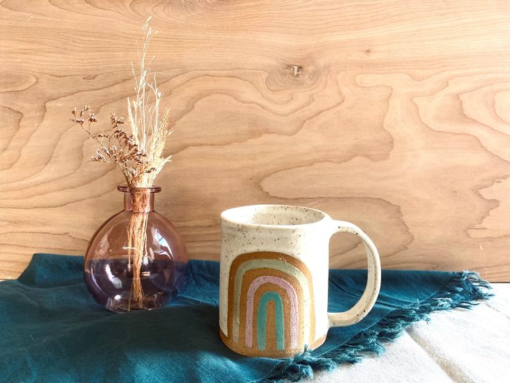 two vases with flowers in them sitting on a blue blanket next to a wooden wall