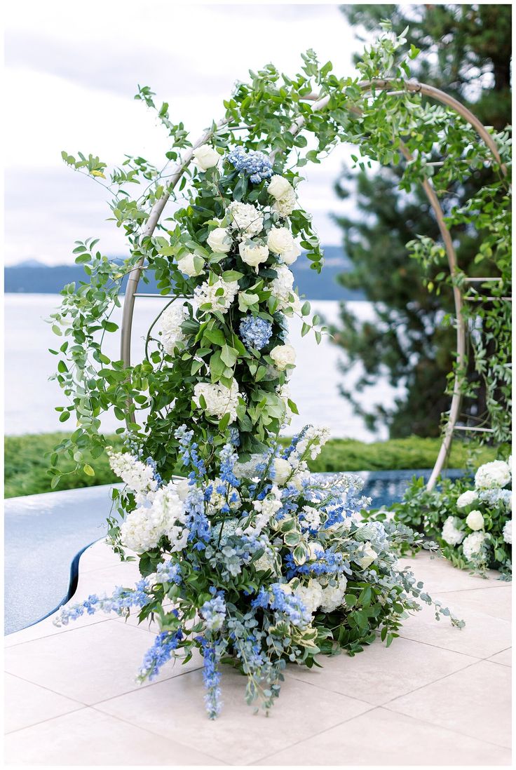 a bouquet of flowers sitting on top of a table next to a pool with water in the background