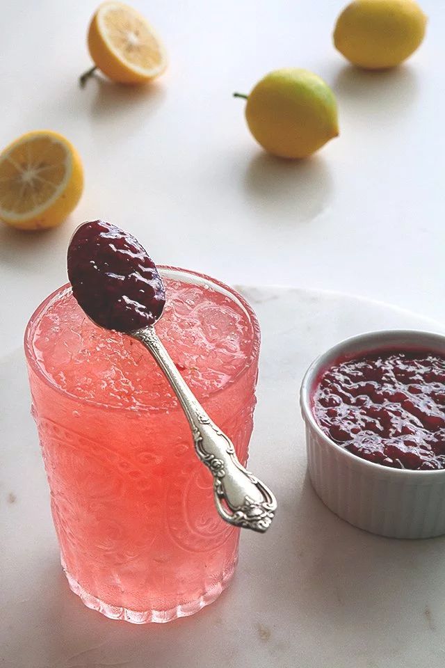 a spoon sitting on top of a glass filled with liquid next to some lemons