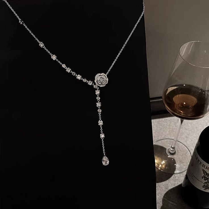 a wine glass sitting next to a silver necklace