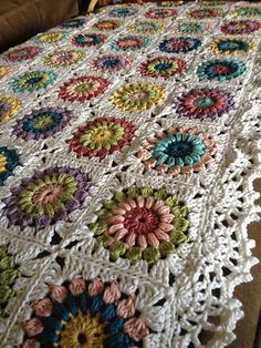 a crocheted blanket with flowers on it sitting on top of a brown couch