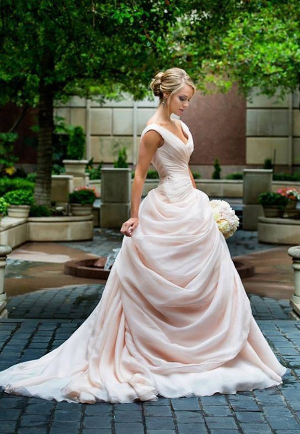 a woman in a wedding dress standing on a brick walkway with trees and bushes behind her