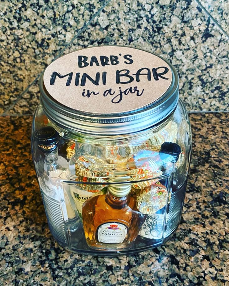 a glass jar filled with lots of bottles on top of a counter next to a bottle opener