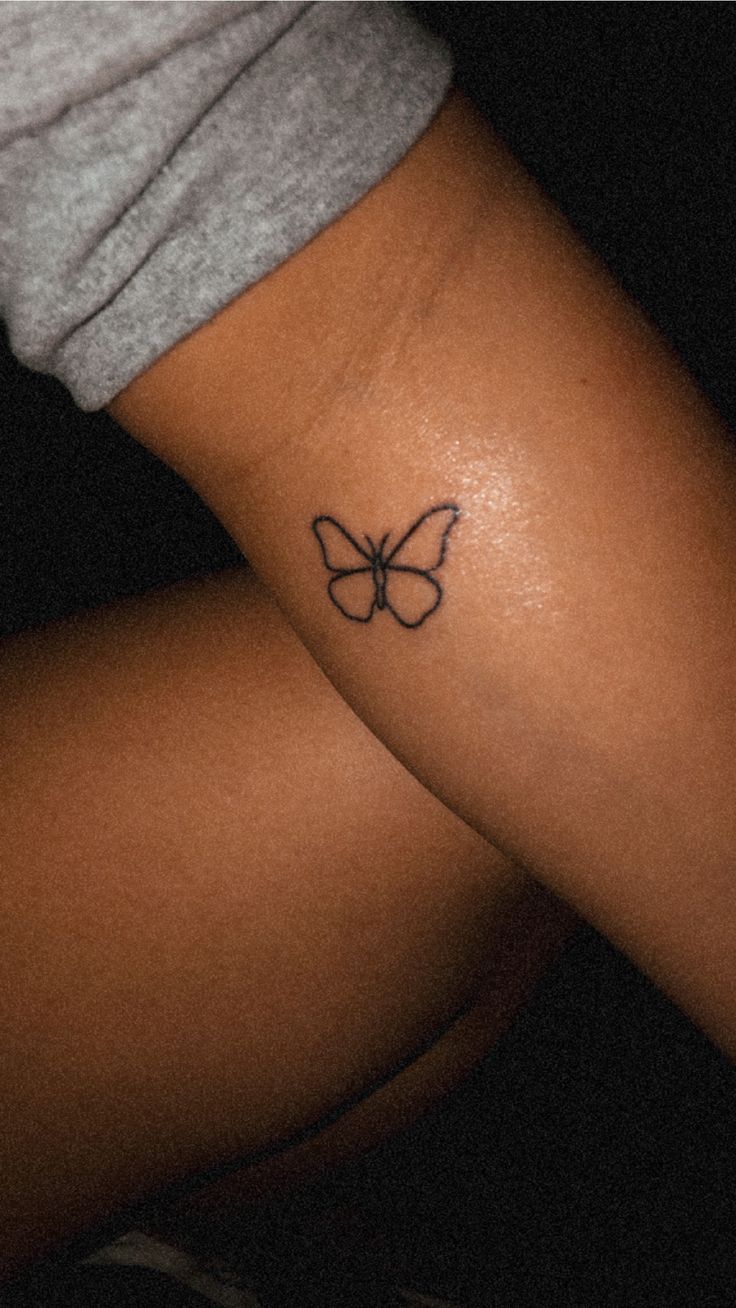 a woman's arm with a small butterfly tattoo on the left side of her leg