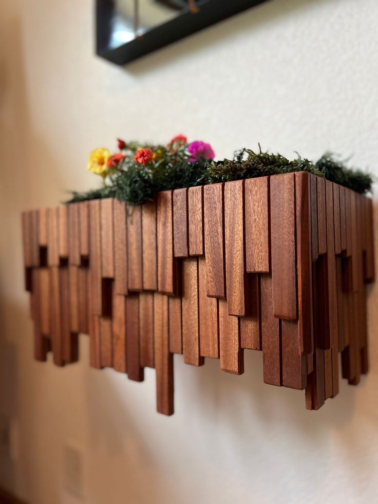 a wooden planter filled with flowers on top of a wall