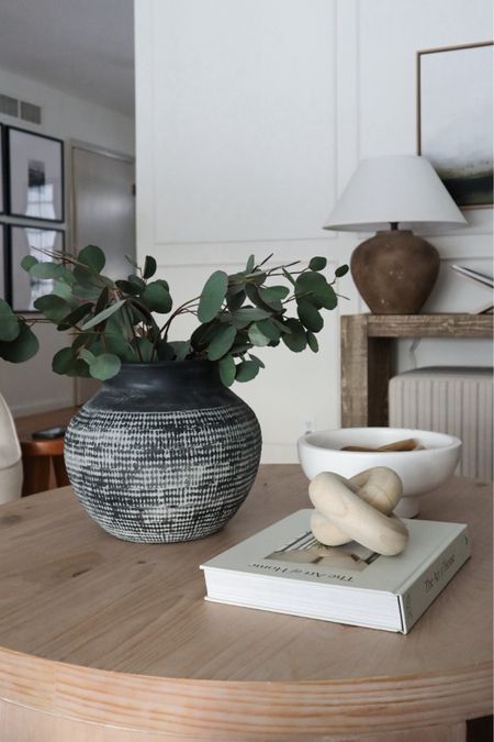 a table with a book, vase and plant on it