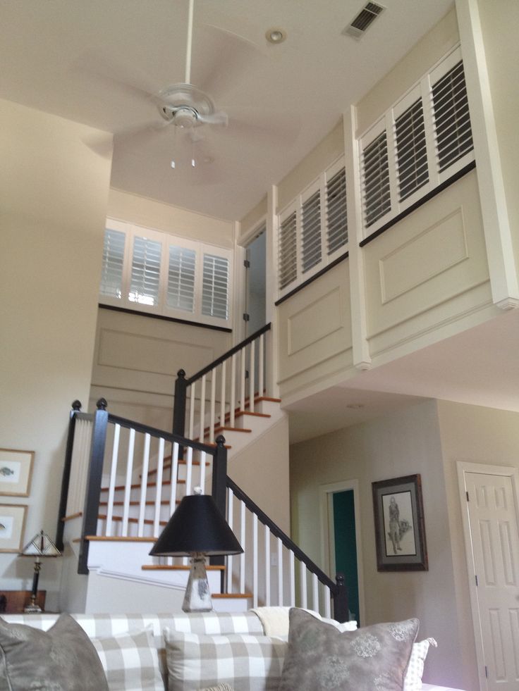 a living room filled with furniture and a stair case above the couch in front of a window