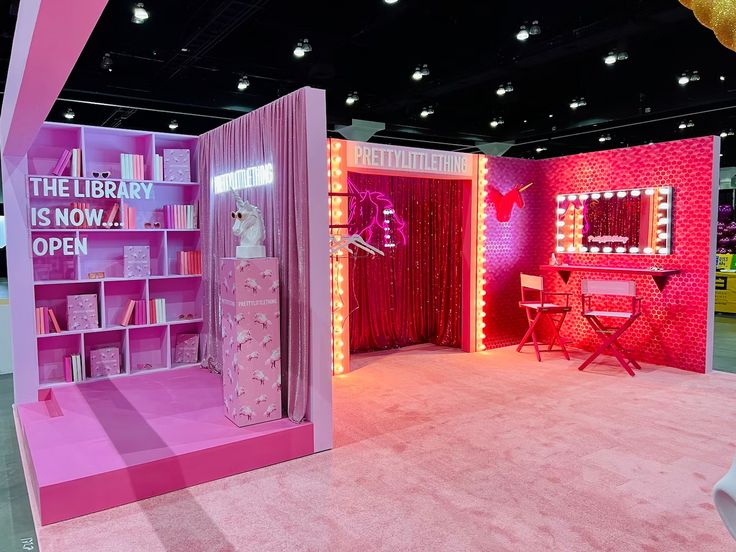 a room with pink furniture and lights on the walls, including a bookcase that says the library is now open