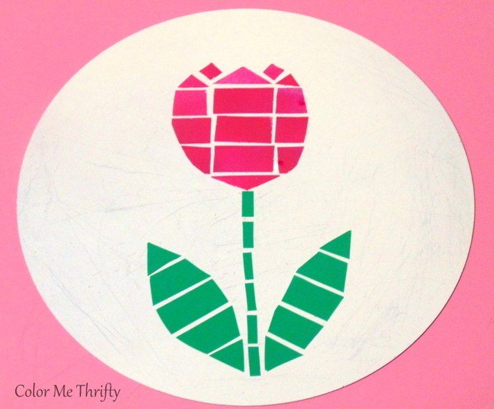 a paper plate with a pink flower on it and green leaves painted on the side