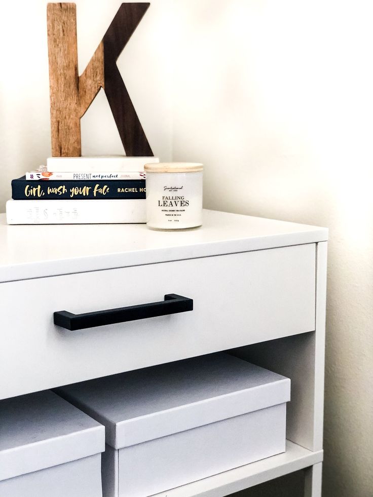 a white dresser with two drawers and a letter k on it's side table