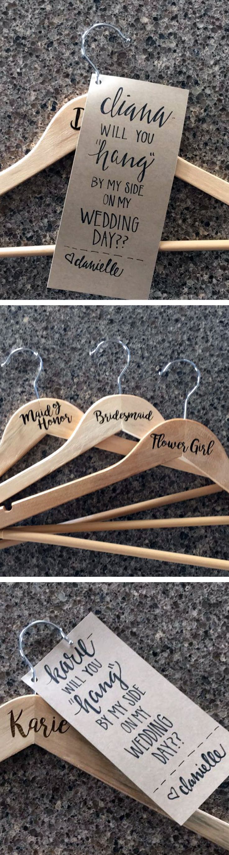 three wooden clothes hangers with handwritten names on them, and one has a sign attached to it