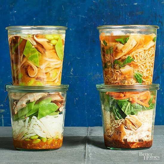 four glass containers filled with food sitting on top of a cement floor next to a blue wall