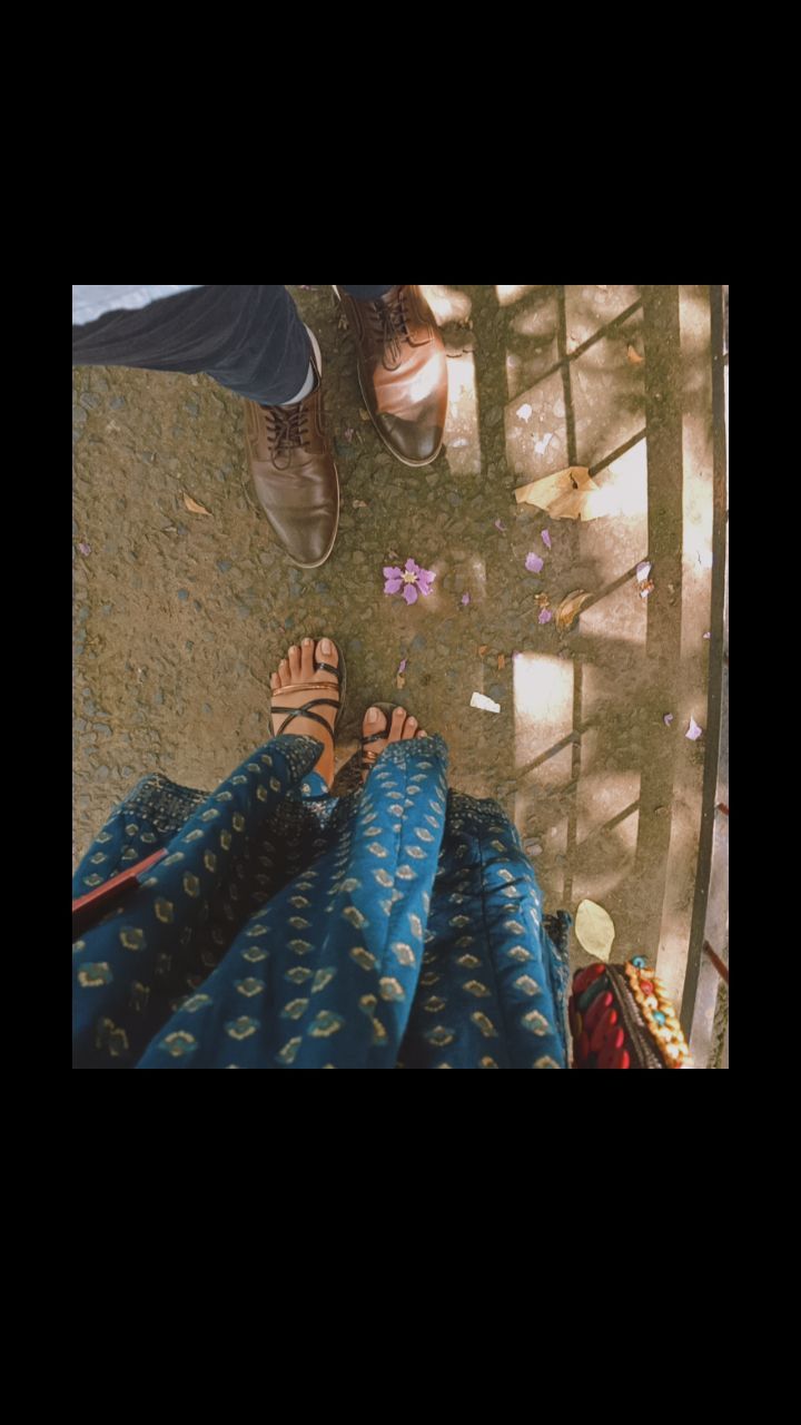 two people standing next to each other with their feet up on the ground and looking down at them