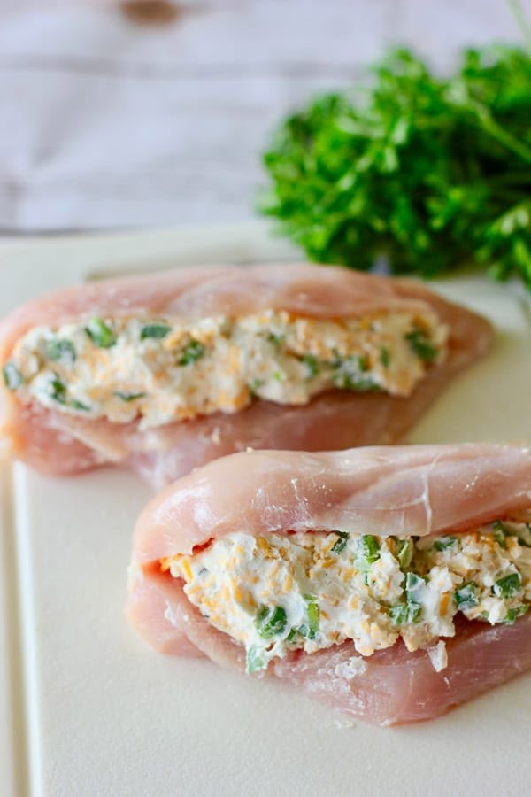 two pieces of meat sitting on top of a white cutting board next to parsley