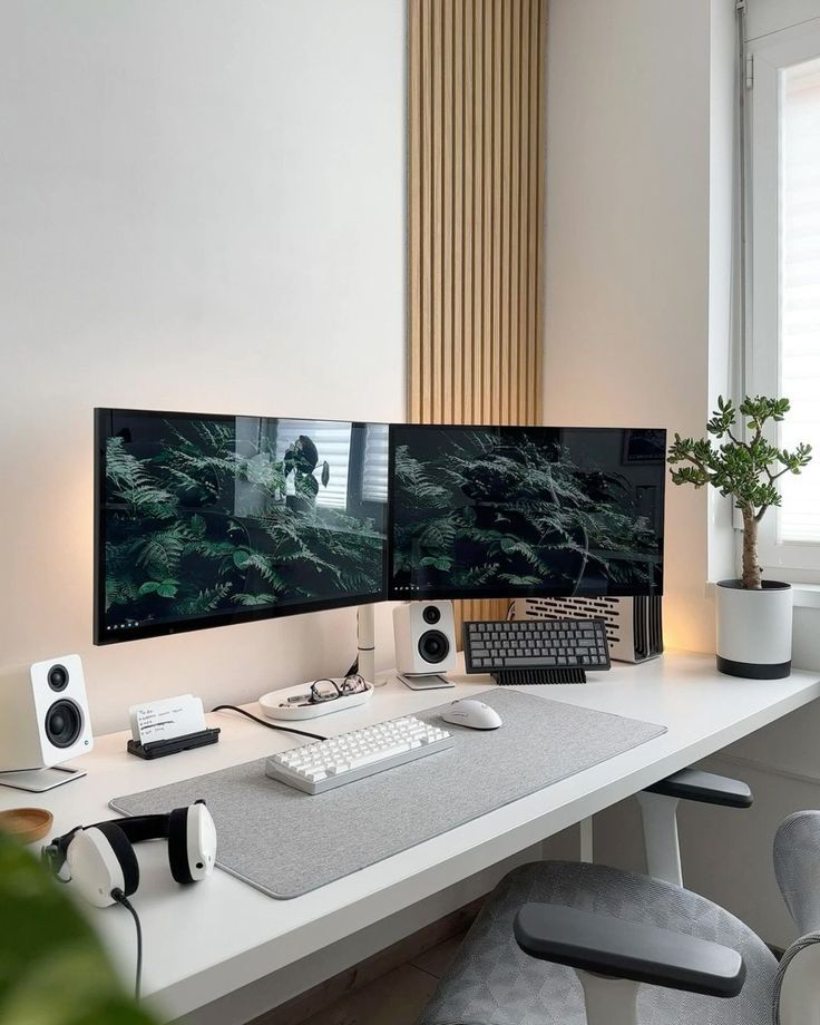 two computer monitors sitting on top of a white desk next to a keyboard and mouse