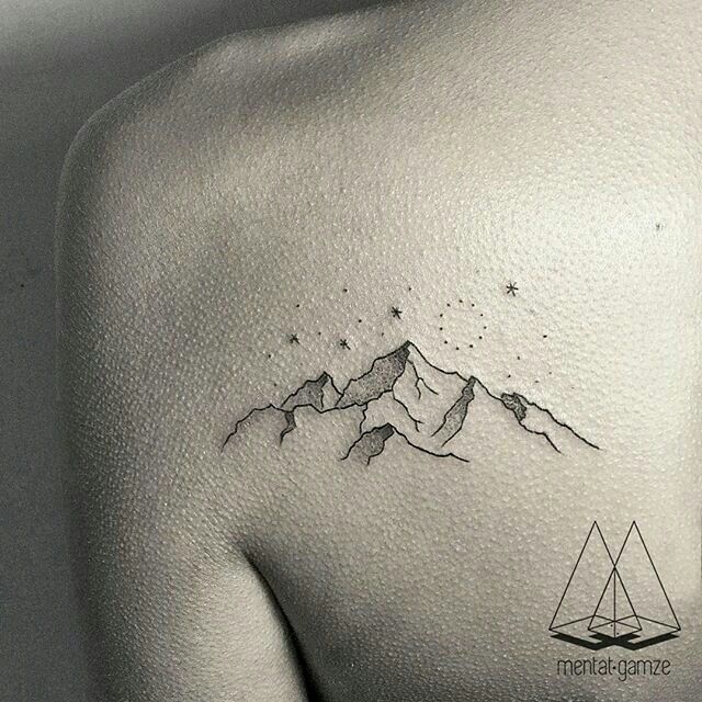 the back of a woman's shoulder with mountains and stars tattoo on her left side