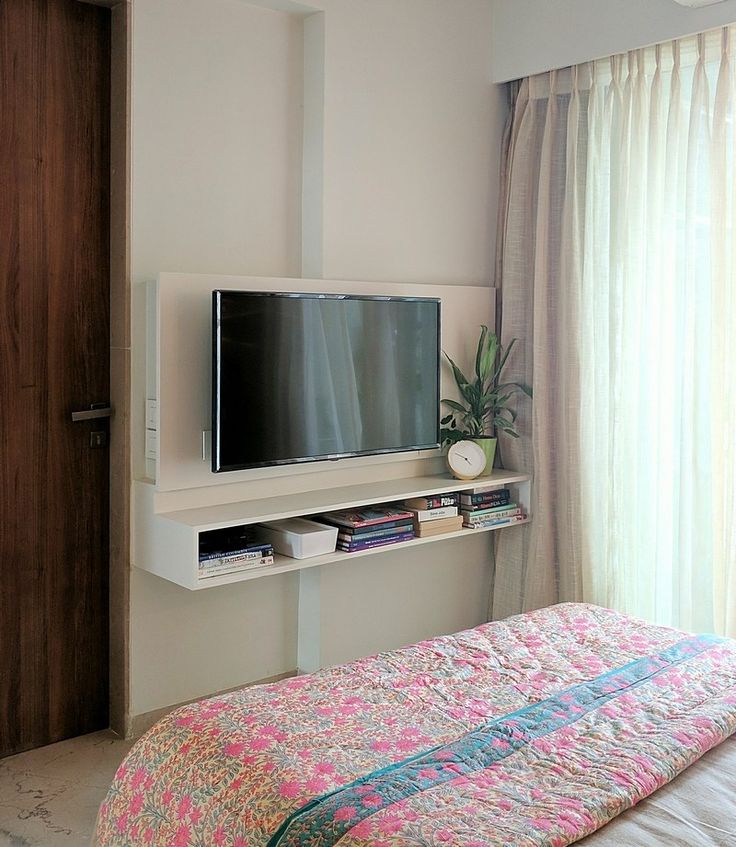 a flat screen tv mounted on the wall above a bed