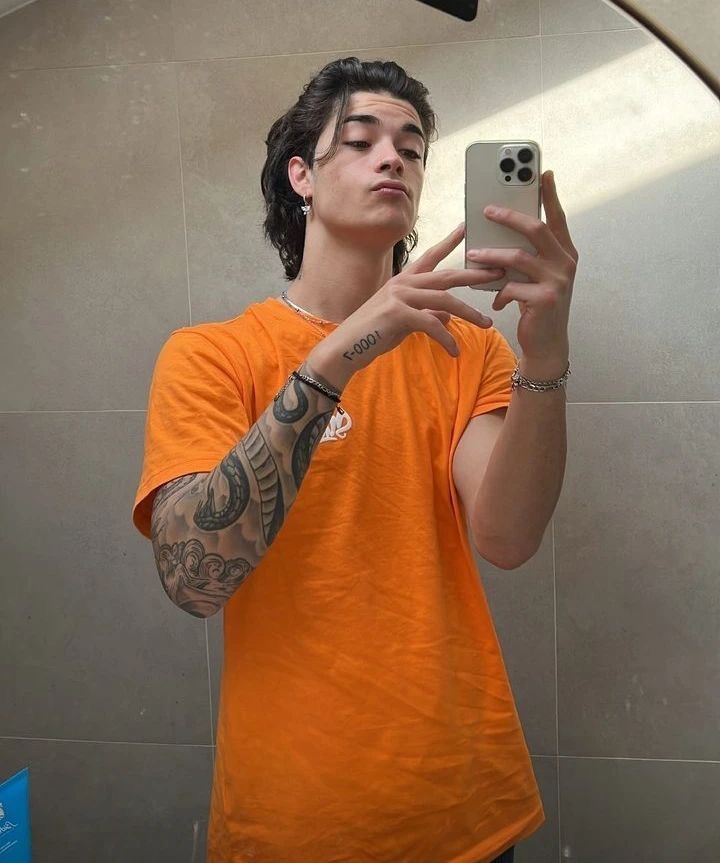 a young man taking a selfie in front of a mirror with his cell phone