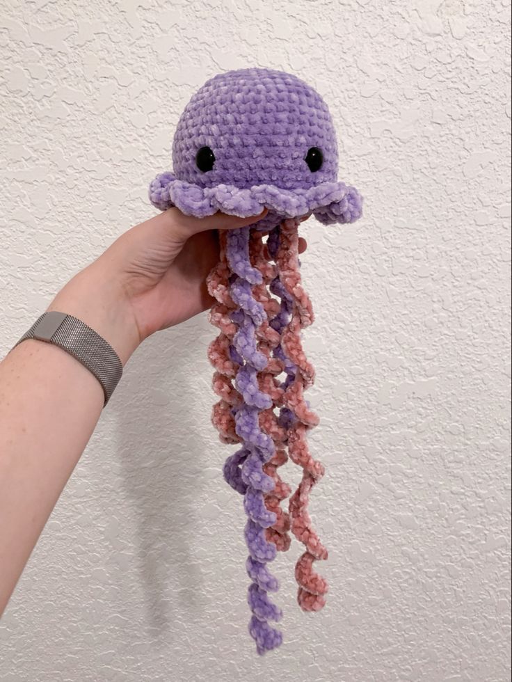 a crocheted octopus is held up in the air by someone's hand