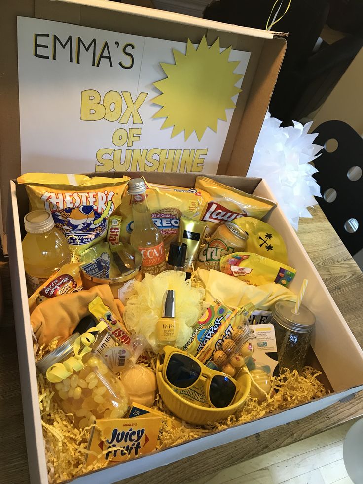 a box filled with snacks and drinks sitting on top of a wooden table next to a sign