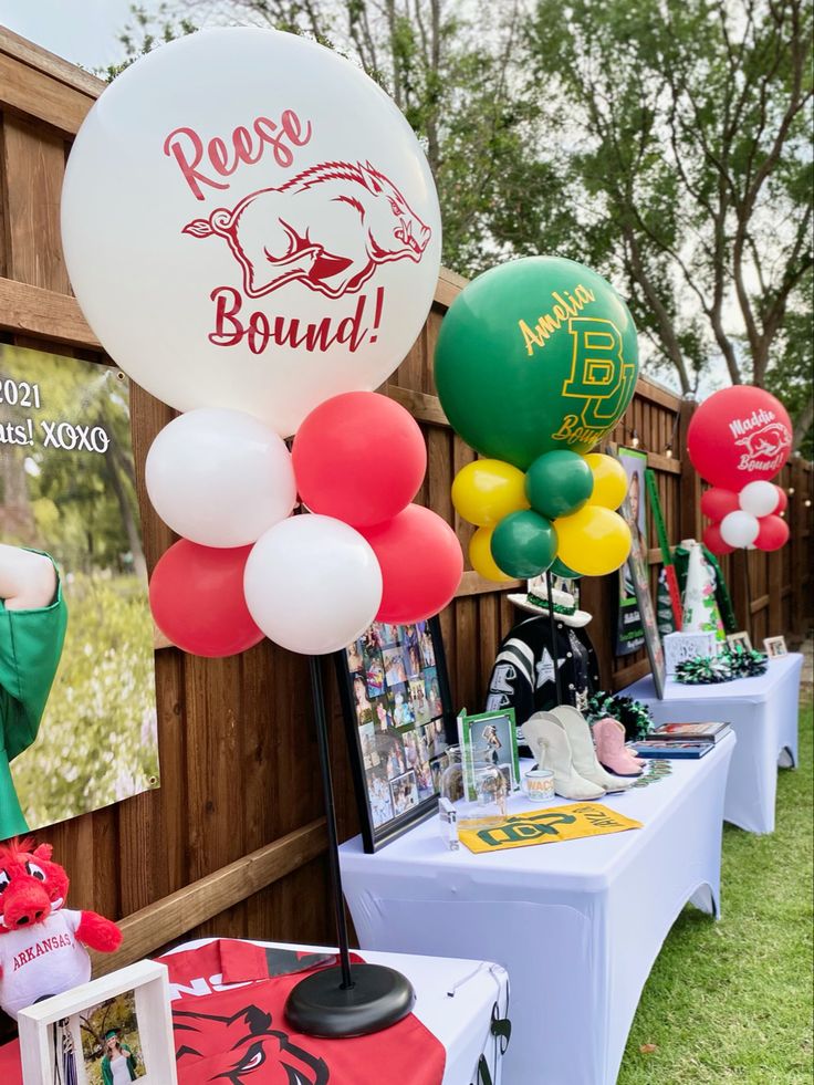 there are many balloons and pictures on the tables at this sports themed birthday party,