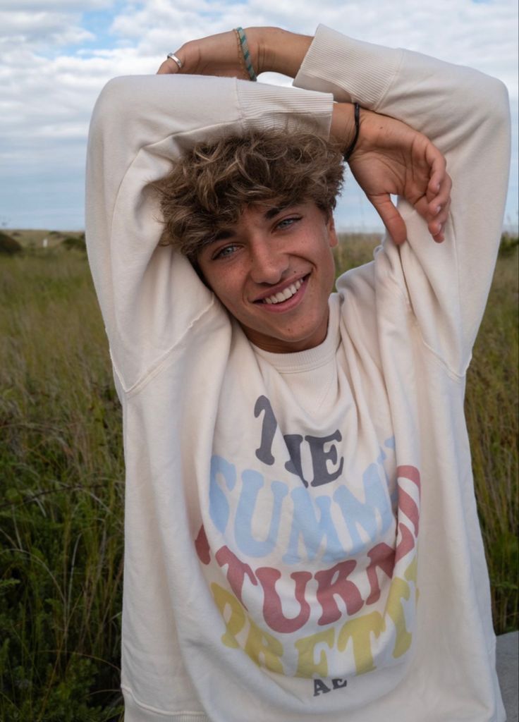 a young man in a white shirt is posing for the camera with his hands on his head