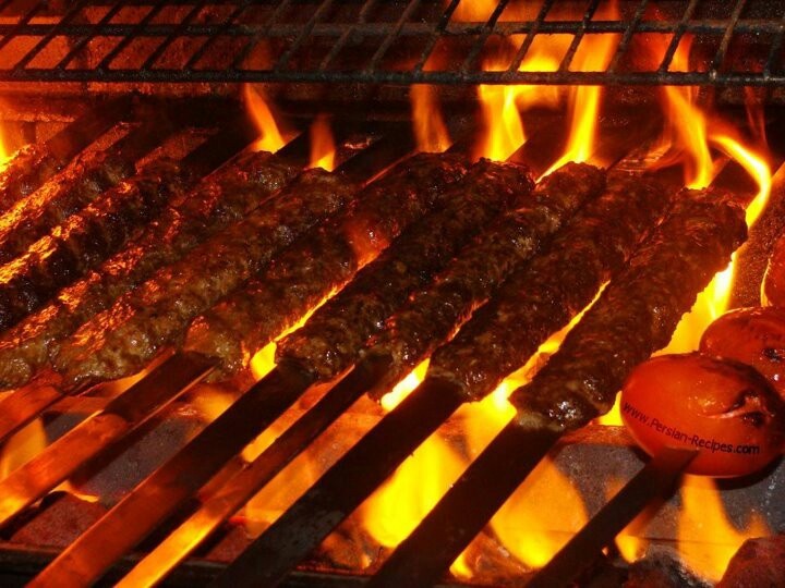 meat is cooking on the grill with flames